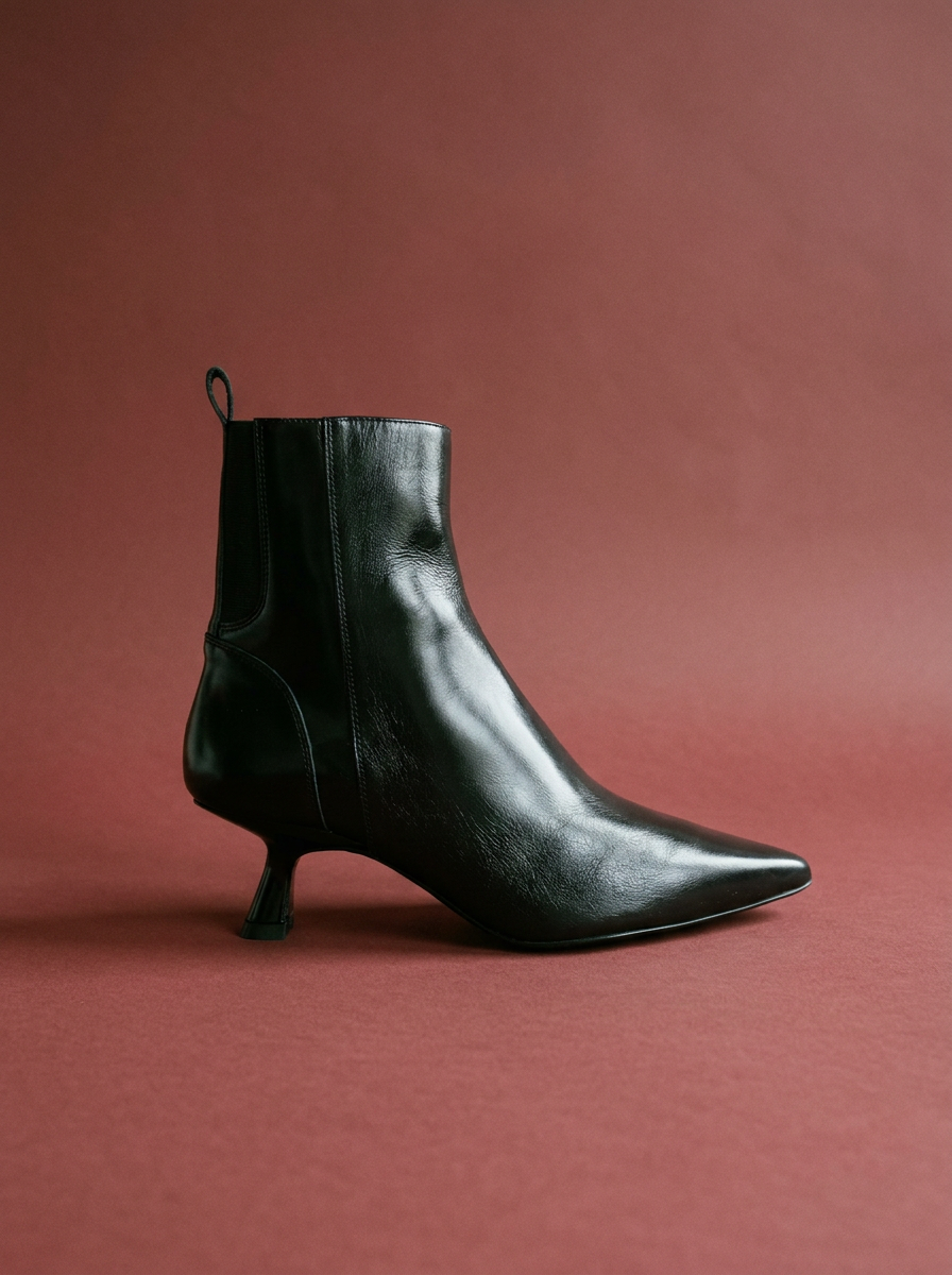 black leather bootie against an oxblood background