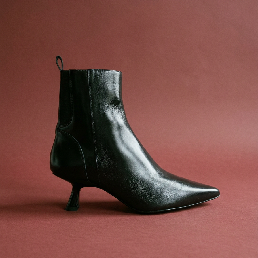 black leather bootie against an oxblood background