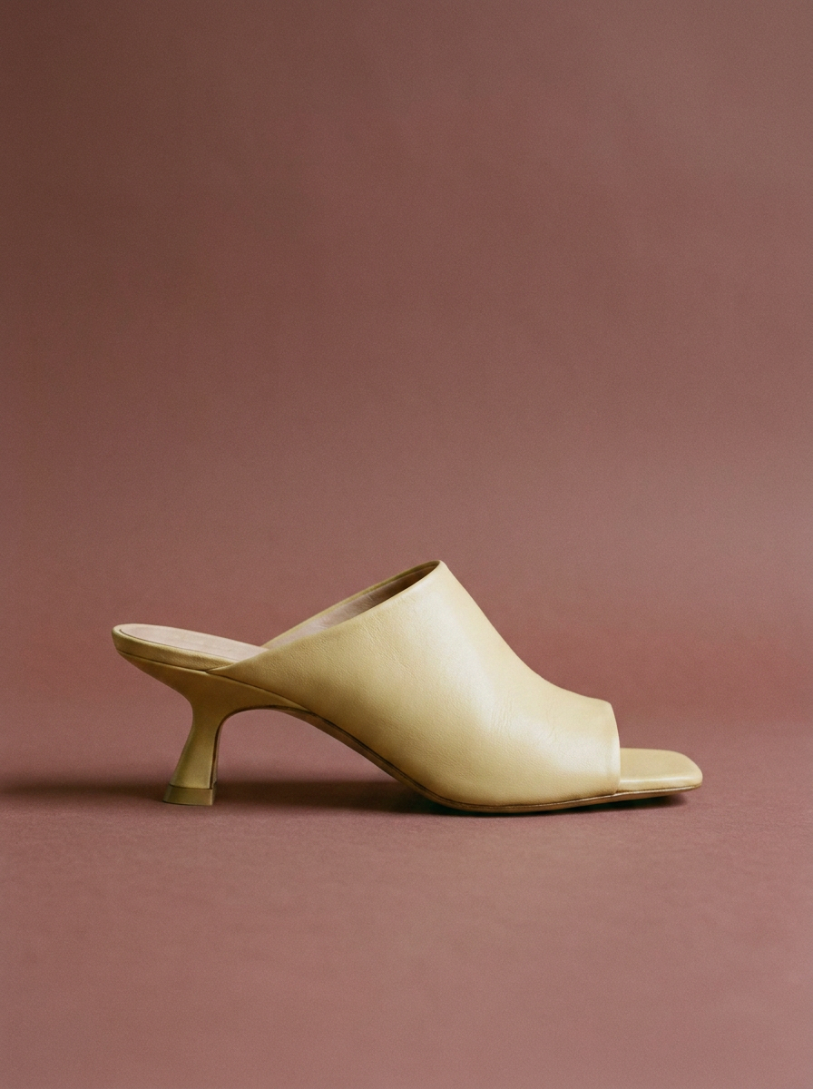 Butter yellow mule on a desaturated oxblood background